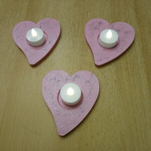 Handbemalte Herz Teelichthalter Rosa aus Holz im 4er Set, jeweils mit farbenfrohen, individuellen Designs. In der Mitte jedes Herzens befindet sich eine Vertiefung für ein kleines Teelicht, das warmes Licht auf das bemalte Holz wirft. Das 4er-Set strahlt Gemütlichkeit und Liebe aus – perfekt als romantische Deko, Geschenk oder Lichtakzent für Valentinstag, Hochzeit oder Alltag.