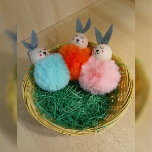 Handgefertigte Pompon-Osterhäschen aus weichem, flauschigem Material in fröhlichen Farben wie Rosa, Gelb, Hellblau, Weiß und Dunkelgrün. Jedes Häschen hat lange graue Filzohren, handbemalte Augen, Nase und rosige Wangen sowie eine graue Aufhängeschlaufe. Die niedlichen Anhänger verbreiten frühlingshafte Osterstimmung an Zweigen, Fenstern oder Geschenken.