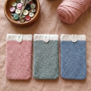 Handgehäkelte Handyhülle Zweifarbige Handyhülle aus weicher, strapazierfähiger Wolle mit dekorativem Knopfverschluss. Die Hülle misst etwa 10 x 16 cm, ist dehnbar und passt sich der Form des Smartphones an. In sanften Pastelltönen gestaltet, schützt sie das Handy vor Kratzern und Stößen – ein stilvolles, handgefertigtes Accessoire mit liebevollen Details.