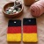 Handgehäkelte Handyhülle Deutschland Handyhülle in den Farben Schwarz, Rot und Gold, angeordnet wie die deutsche Flagge. Aus robustem Wollgarn gefertigt, mit weicher Struktur und sicherem Knopfverschluss oben. Schützt das Smartphone vor Kratzern und Stößen. Erhältlich in zwei Größen – ein handgemachtes Accessoire für Fans und Liebhaber deutscher Farben.