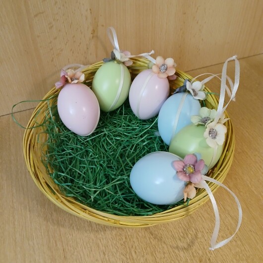 Handgemachte Ostereier in sanften Pastellfarben wie Rosa, Hellblau und Mintgrün, jeweils mit weißen Satinbändern und kleinen, farblich abgestimmten Blütenapplikationen verziert. Die Eier haben eine leicht schimmernde Oberfläche und hängen an eleganten Satinbändern. Die zarten Blüten und weichen Farben verleihen der Osterdeko einen eleganten, frühlingshaften und verspielten Look.