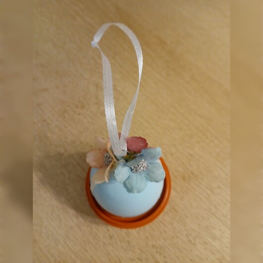 Handgemachte Ostereier in sanften Pastellfarben wie Rosa, Hellblau und Mintgrün, jeweils mit weißen Satinbändern und kleinen, farblich abgestimmten Blütenapplikationen verziert. Die Eier haben eine leicht schimmernde Oberfläche und hängen an eleganten Satinbändern. Die zarten Blüten und weichen Farben verleihen der Osterdeko einen eleganten, frühlingshaften und verspielten Look.