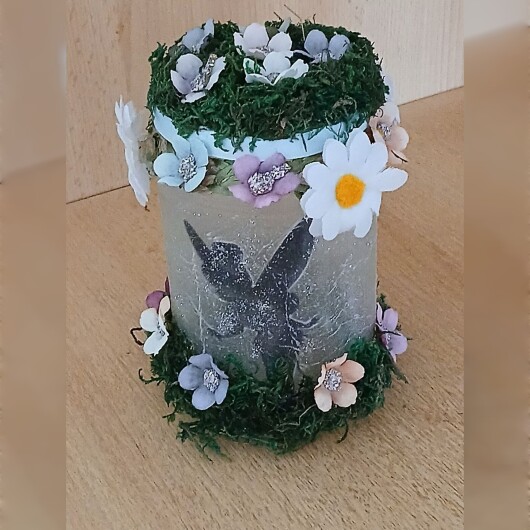 Handgefertigtes Feenglas Fee Motiv 1 mit romantischem Feenmotiv, verziert mit blauem Satinband, feinem Glitzerstaub und einer kleinen Mooslandschaft auf dem Deckel. Umgeben von zarten Kunstblumen wirkt das Glas wie ein leuchtender Miniaturgarten. Im Inneren sorgt ein flackerndes LED-Teelicht für warmes, magisches Licht – ein märchenhaftes Deko- und Nachtlicht für jeden Raum.