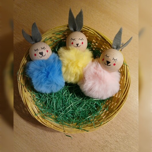 Handgefertigte Pompon-Osterhäschen aus weichem, flauschigem Material in fröhlichen Farben wie Rosa, Gelb, Hellblau, Weiß und Dunkelgrün. Jedes Häschen hat lange graue Filzohren, handbemalte Augen, Nase und rosige Wangen sowie eine graue Aufhängeschlaufe. Die niedlichen Anhänger verbreiten frühlingshafte Osterstimmung an Zweigen, Fenstern oder Geschenken.