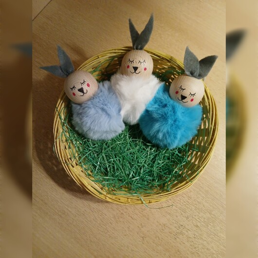 Handgefertigte Pompon-Osterhäschen aus weichem, flauschigem Material in fröhlichen Farben wie Rosa, Gelb, Hellblau, Weiß und Dunkelgrün. Jedes Häschen hat lange graue Filzohren, handbemalte Augen, Nase und rosige Wangen sowie eine graue Aufhängeschlaufe. Die niedlichen Anhänger verbreiten frühlingshafte Osterstimmung an Zweigen, Fenstern oder Geschenken.