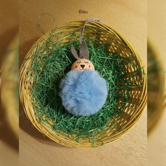 Handgefertigte Pompon-Osterhäschen Blau aus weichem, flauschigem Material in fröhlichen Farben wie Rosa, Gelb, Hellblau, Weiß und Dunkelgrün. Jedes Häschen hat lange graue Filzohren, handbemalte Augen, Nase und rosige Wangen sowie eine graue Aufhängeschlaufe. Die niedlichen Anhänger verbreiten frühlingshafte Osterstimmung an Zweigen, Fenstern oder Geschenken.