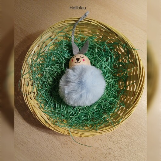 Handgefertigte Pompon-Osterhäschen Hellblau aus weichem, flauschigem Material in fröhlichen Farben wie Rosa, Gelb, Hellblau, Weiß und Dunkelgrün. Jedes Häschen hat lange graue Filzohren, handbemalte Augen, Nase und rosige Wangen sowie eine graue Aufhängeschlaufe. Die niedlichen Anhänger verbreiten frühlingshafte Osterstimmung an Zweigen, Fenstern oder Geschenken.