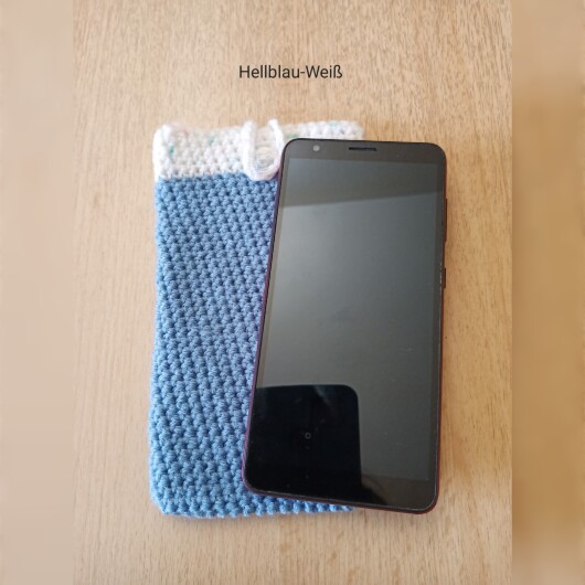 Handgehäkelte zweifarbige Handyhülle Hellblau-Weiß aus weicher, strapazierfähiger Wolle mit dekorativem Knopfverschluss. Die Hülle misst etwa 10 x 16 cm, ist dehnbar und passt sich der Form des Smartphones an. In sanften Pastelltönen gestaltet, schützt sie das Handy vor Kratzern und Stößen – ein stilvolles, handgefertigtes Accessoire mit liebevollen Details.
