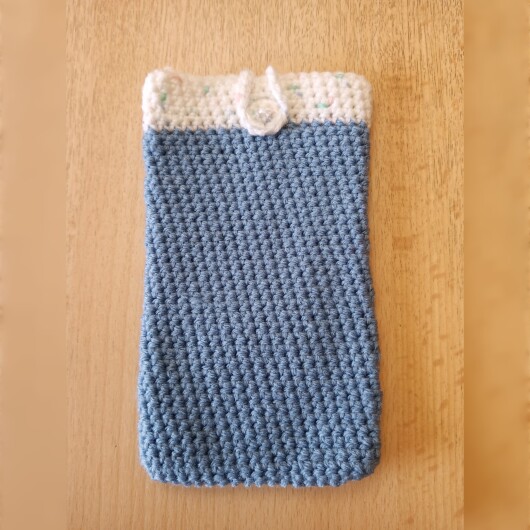Handgehäkelte zweifarbige Handyhülle Hellblau-Weiß aus weicher, strapazierfähiger Wolle mit dekorativem Knopfverschluss. Die Hülle misst etwa 10 x 16 cm, ist dehnbar und passt sich der Form des Smartphones an. In sanften Pastelltönen gestaltet, schützt sie das Handy vor Kratzern und Stößen – ein stilvolles, handgefertigtes Accessoire mit liebevollen Details.