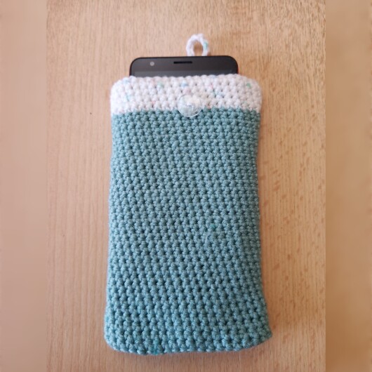 Handgehäkelte zweifarbige Handyhülle Mintgrün-Weiß aus weicher, strapazierfähiger Wolle mit dekorativem Knopfverschluss. Die Hülle misst etwa 10 x 16 cm, ist dehnbar und passt sich der Form des Smartphones an. In sanften Pastelltönen gestaltet, schützt sie das Handy vor Kratzern und Stößen – ein stilvolles, handgefertigtes Accessoire mit liebevollen Details.