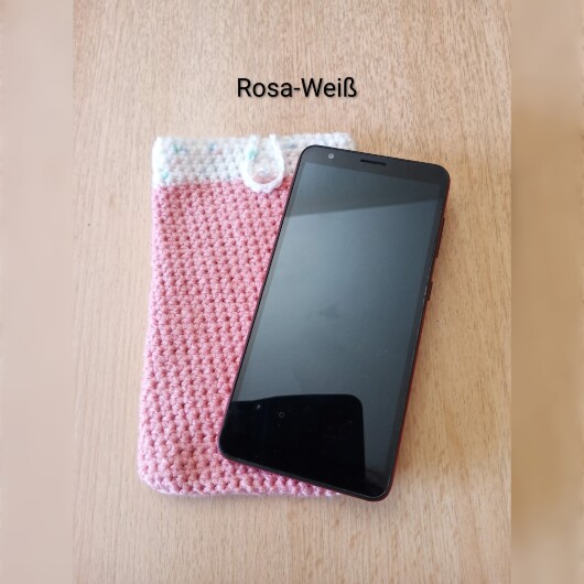 Handgehäkelte zweifarbige Handyhülle Rosa-Weiß aus weicher, strapazierfähiger Wolle mit dekorativem Knopfverschluss. Die Hülle misst etwa 10 x 16 cm, ist dehnbar und passt sich der Form des Smartphones an. In sanften Pastelltönen gestaltet, schützt sie das Handy vor Kratzern und Stößen – ein stilvolles, handgefertigtes Accessoire mit liebevollen Details.