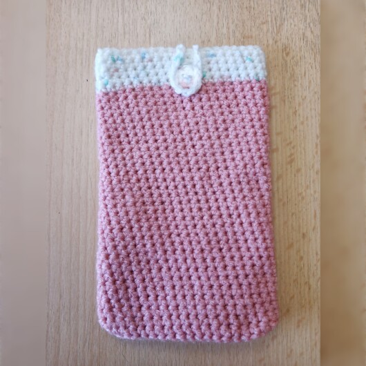 Handgehäkelte zweifarbige Handyhülle Rosa-Weiß aus weicher, strapazierfähiger Wolle mit dekorativem Knopfverschluss. Die Hülle misst etwa 10 x 16 cm, ist dehnbar und passt sich der Form des Smartphones an. In sanften Pastelltönen gestaltet, schützt sie das Handy vor Kratzern und Stößen – ein stilvolles, handgefertigtes Accessoire mit liebevollen Details.