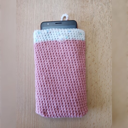 Handgehäkelte zweifarbige Handyhülle Rosa-Weiß aus weicher, strapazierfähiger Wolle mit dekorativem Knopfverschluss. Die Hülle misst etwa 10 x 16 cm, ist dehnbar und passt sich der Form des Smartphones an. In sanften Pastelltönen gestaltet, schützt sie das Handy vor Kratzern und Stößen – ein stilvolles, handgefertigtes Accessoire mit liebevollen Details.