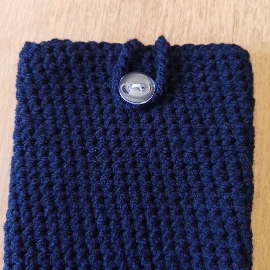 Handgehäkelte Handyhülle Dunkelblau aus weicher, strapazierfähiger Baumwolle mit dekorativem Knopfverschluss. Etwa 10 x 18 cm groß, dehnbar und passend für viele Smartphone-Modelle. Schützt das Handy vor Kratzern und leichten Stößen, handgefertigt in verschiedenen Farben – jedes Stück ein individuelles Unikat mit liebevollen Details.