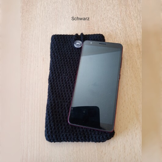 Handgehäkelte Handyhülle Schwarz aus weicher, strapazierfähiger Baumwolle mit dekorativem Knopfverschluss. Etwa 10 x 18 cm groß, dehnbar und passend für viele Smartphone-Modelle. Schützt das Handy vor Kratzern und leichten Stößen, handgefertigt in verschiedenen Farben – jedes Stück ein individuelles Unikat mit liebevollen Details.