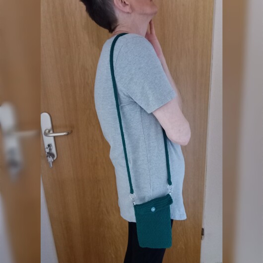 Handgehäkelte Handytasche Dunkelgrün aus hochwertigem Garn mit gleichmäßiger Struktur und Knopfverschluss. Die Tasche misst etwa 12 x 20 cm, bietet Platz für ein Smartphone und kleine Alltagsgegenstände. Mit abnehmbarem Schultergurt, der wahlweise als Umhängetasche oder Handyhülle genutzt werden kann. In verschiedenen Farben erhältlich – ein handgemachtes, stilvolles und nachhaltiges Accessoire.