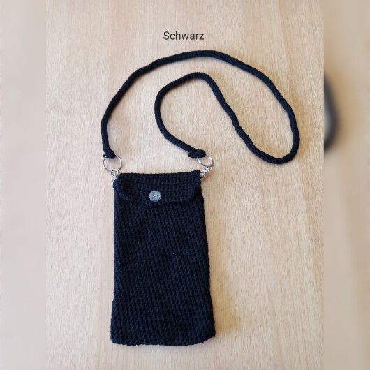 Handgehäkelte Handytasche Schwarz aus hochwertigem Garn mit gleichmäßiger Struktur und Knopfverschluss. Die Tasche misst etwa 12 x 20 cm, bietet Platz für ein Smartphone und kleine Alltagsgegenstände. Mit abnehmbarem Schultergurt, der wahlweise als Umhängetasche oder Handyhülle genutzt werden kann. In verschiedenen Farben erhältlich – ein handgemachtes, stilvolles und nachhaltiges Accessoire.