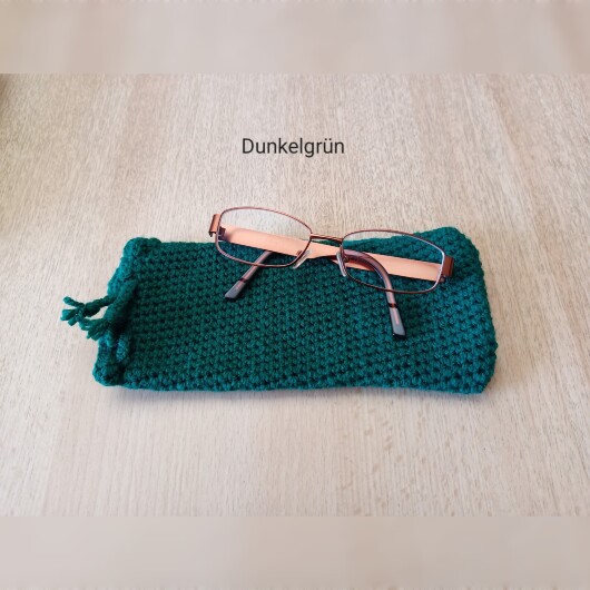 Handgehäkeltes Brillenetui Dunkelgrün aus weicher Baumwolle mit handgeflochtenem Kordelzug. Das etwa 9 x 20 cm große Etui bietet Platz für Lese-, Sonnen- oder Sehbrillen und schützt sie zuverlässig vor Kratzern und leichten Stößen. Leichtes, schlankes Design mit rustikalem Charme – in verschiedenen Farben erhältlich, handgefertigt und nachhaltig hergestellt.
