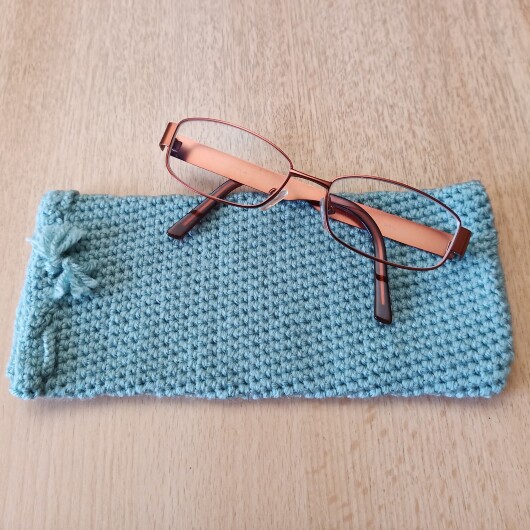Handgehäkeltes Brillenetui Mintgrün aus weicher Baumwolle mit handgeflochtenem Kordelzug. Das etwa 9 x 20 cm große Etui bietet Platz für Lese-, Sonnen- oder Sehbrillen und schützt sie zuverlässig vor Kratzern und leichten Stößen. Leichtes, schlankes Design mit rustikalem Charme – in verschiedenen Farben erhältlich, handgefertigt und nachhaltig hergestellt.