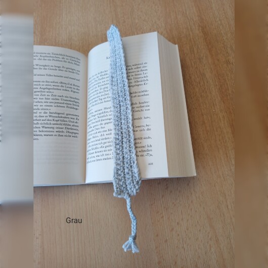 Handgehäkeltes Lesezeichen Grau aus feiner Baumwolle mit filigraner Häkelstruktur und handgeflochtenem Abschlussband. Etwa 2 x 25 cm groß, flach und leicht, ideal zum Markieren von Buchseiten, ohne das Buch zu beschädigen. In verschiedenen Farben erhältlich – jedes Stück ein handgefertigtes Unikat für stilvolles, liebevolles Lesen.