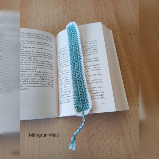 Handgehäkeltes Lesezeichen Mintgrün-Weiß aus feiner Baumwolle mit filigraner Häkelstruktur und handgeflochtenem Abschlussband. Etwa 2 x 25 cm groß, flach und leicht, ideal zum Markieren von Buchseiten, ohne das Buch zu beschädigen. In verschiedenen Farben erhältlich – jedes Stück ein handgefertigtes Unikat für stilvolles, liebevolles Lesen.