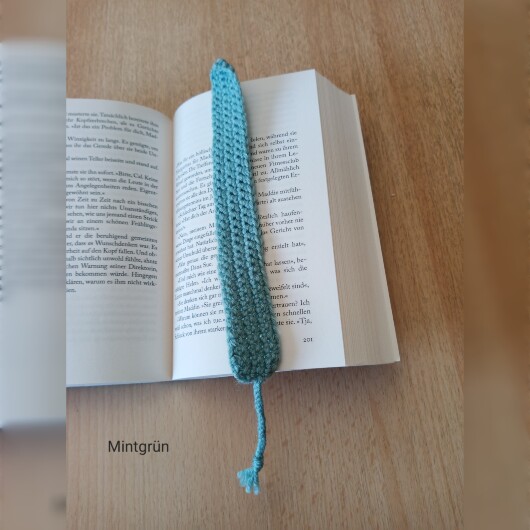 Handgehäkeltes Lesezeichen Mintgrün aus feiner Baumwolle mit filigraner Häkelstruktur und handgeflochtenem Abschlussband. Etwa 2 x 25 cm groß, flach und leicht, ideal zum Markieren von Buchseiten, ohne das Buch zu beschädigen. In verschiedenen Farben erhältlich – jedes Stück ein handgefertigtes Unikat für stilvolles, liebevolles Lesen.
