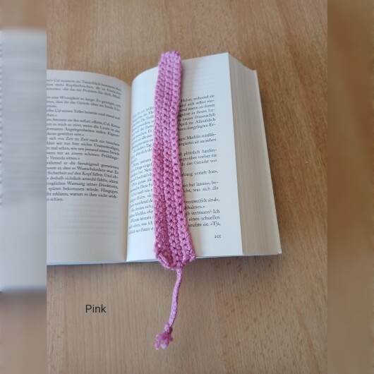 Handgehäkeltes Lesezeichen Pink aus feiner Baumwolle mit filigraner Häkelstruktur und handgeflochtenem Abschlussband. Etwa 2 x 25 cm groß, flach und leicht, ideal zum Markieren von Buchseiten, ohne das Buch zu beschädigen. In verschiedenen Farben erhältlich – jedes Stück ein handgefertigtes Unikat für stilvolles, liebevolles Lesen.