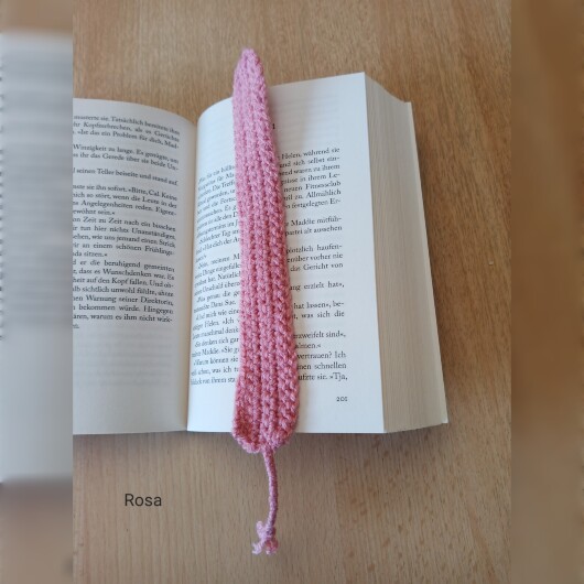 Handgehäkeltes Lesezeichen Rosa aus feiner Baumwolle mit filigraner Häkelstruktur und handgeflochtenem Abschlussband. Etwa 2 x 25 cm groß, flach und leicht, ideal zum Markieren von Buchseiten, ohne das Buch zu beschädigen. In verschiedenen Farben erhältlich – jedes Stück ein handgefertigtes Unikat für stilvolles, liebevolles Lesen.