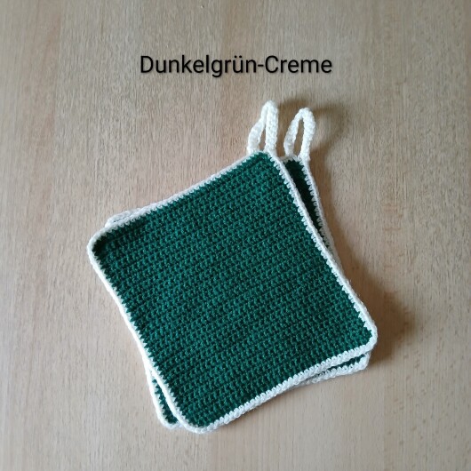 Handgehäkeltes Topflappen-Set Dunkelgrün-Creme aus robustem Baumwollgarn, quadratisch mit ca. 16 x 16 cm Größe. Die gleichmäßige Häkelstruktur sorgt für Hitzeschutz beim Kochen und Backen. Jeder Topflappen hat eine stabile Aufhängeschlaufe und ist wahlweise einfarbig oder mit farbigem Rand gestaltet – ein dekorativer, funktionaler Küchenhelfer in Handarbeit.
